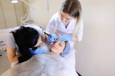 Profesyonel güzellik uzmanı hemşire dolapla adlı kadın için kalıcı makyaj yapma.