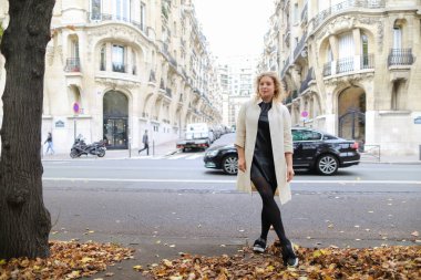 Düşen yapraklar yol ve binaların arka planda yakın duran beyaz kadın.