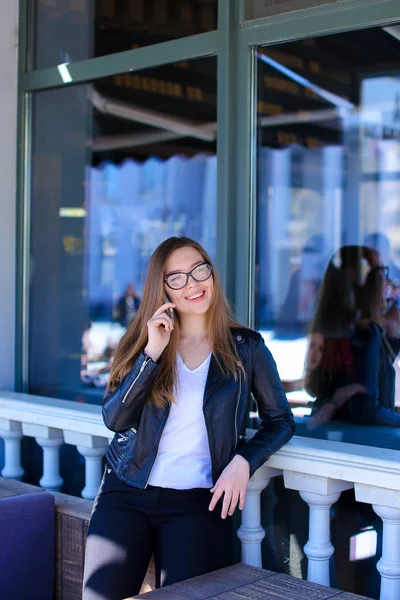 Mulher bonito em óculos falando por smartphone no café de rua . — Fotografia de Stock
