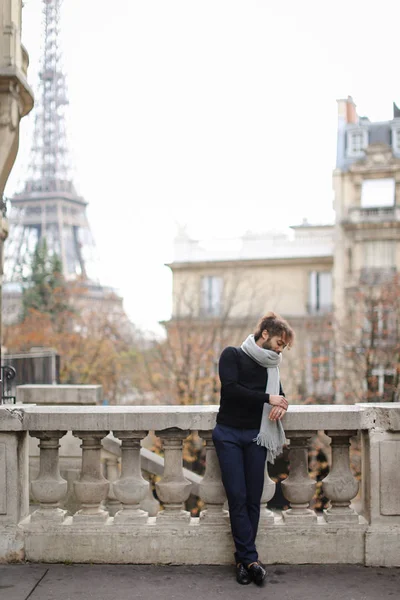 Afro Amerikaanse man die in de buurt van concrete trapleuning met de achtergrond van de Eiffeltoren in Parijs. — Stockfoto