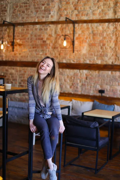 Satisfied girl sitting near table in cozy cafe with unusual interior.