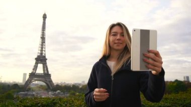 Neşeli kadın yapma video ara Eyfel Kulesi arka plan ağır çekimde tabletiyle tarafından.