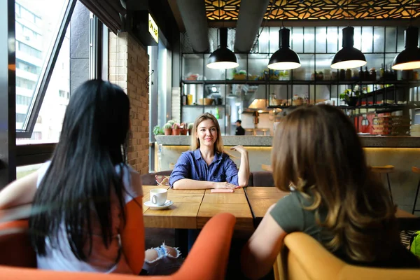 Europeiske kvinner som sitter på en koselig kafe og smiler og drikker kaffe . – stockfoto