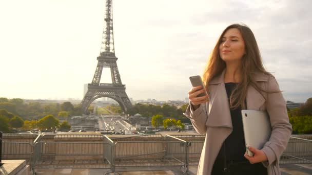 Gyönyörű nő állandó Eiffel-torony közelében, hordozható és smartphone. — Stock videók