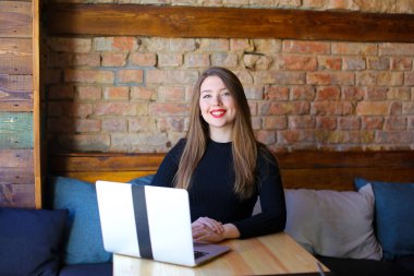 Kafede dizüstü kullanarak kırmızı dudaklar ile gülümseyen kız.