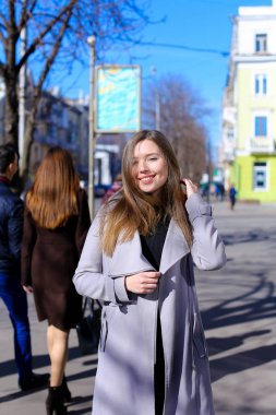 Açık havada geziniyor ve siyah elbise ile gri ceket giyen sevimli kadın.