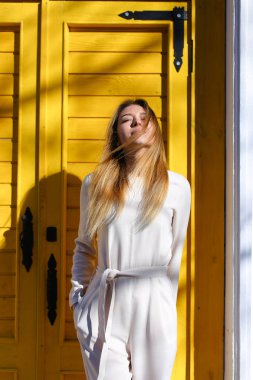 Beyaz takım ayakta sarı kapı yakınındaki güneş ışınları giyen oldukça beyaz kız.