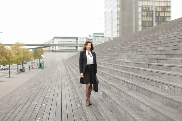 Ευρωπαϊκό επιχειρηματίας που στέκεται πάνω σε σκάλες με τσάντα και ψηλά κτίρια στο φόντο. — Φωτογραφία Αρχείου