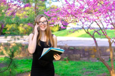 Yanında çiçek açan ağaçlar yakınındaki smartphone ile ortak konuşurken Sekreteri.