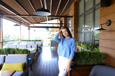 Güzel kadın smartpone, sokak kafe ayakta kot gömlek giymiş.