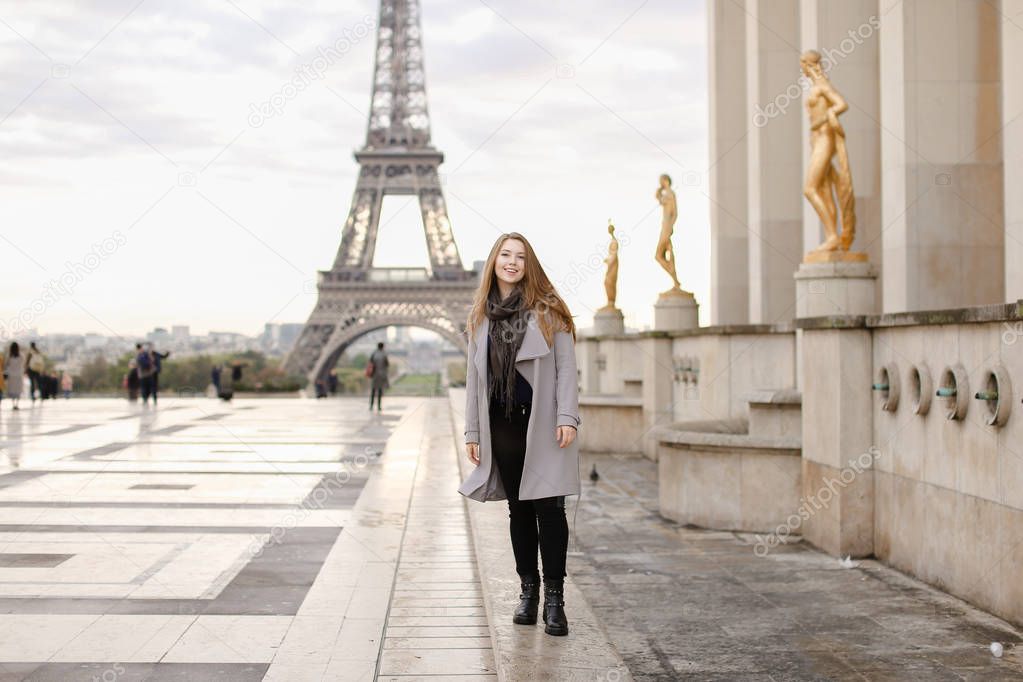 Pretty woman standing on Trocadero square near gilded statues and Eiffel Tower.