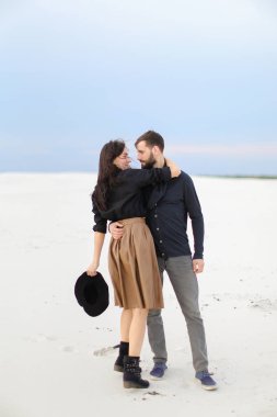 Etek giyen ve şapka, kış kar arka plan tutmak genç jentleman hugginng gülümseyen kadın.