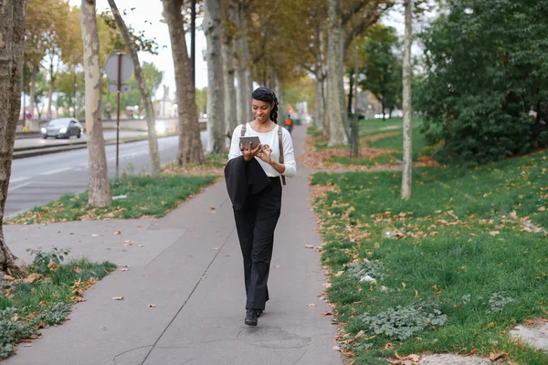 Estudiante joven afroamericano caminando con tableta en el parque de otoño, usando mochila . — Foto de Stock