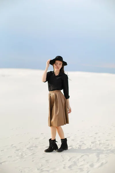 Giovane ragazza caucasica che indossa gonna, camicetta nera con cappello e in piedi sulla neve . — Foto Stock
