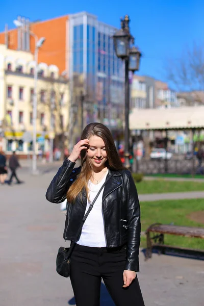 Bella donna che cammina in città e indossa giacca di pelle . — Foto Stock