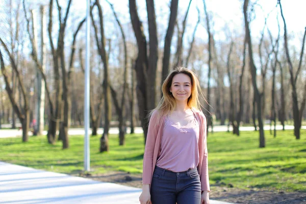 Menina positiva andando no parque e sorrindo . — Fotografia de Stock