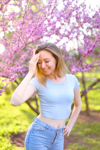 Gelukkig lachend meisje met bloeiende boom achtergrond. — Stockfoto