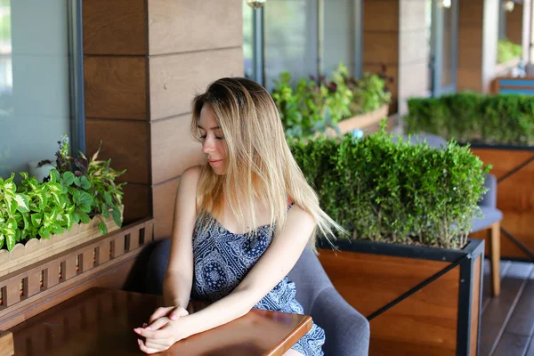 Mujer joven sentada en la cafetería y descansando cerca de plantas de habitación . —  Fotos de Stock