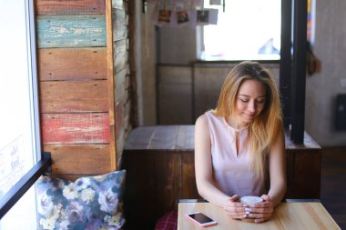 Bayan tablo cam fincan kahve ile yakınındaki rahat kafede oturan ve smartphone kullanarak iletişim kurma.