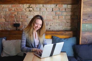 Bayan tablo cam fincan kahve ile yakınındaki rahat kafede oturan ve dizüstü bilgisayar kullanarak iletişim kurma.