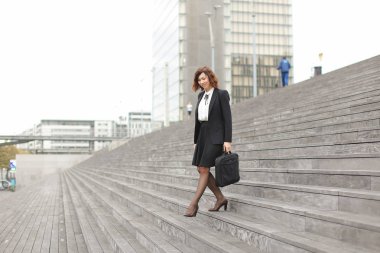 Yüksek binaların arka planda merdivenlerde aşağıya Amerikan kadın Yöneticisi.