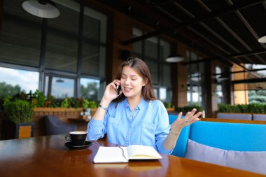 Avrupa öğrenci kafede dizüstü bilgisayar ve bir kahve ile dinlenme Smartphone ile konuşmak.