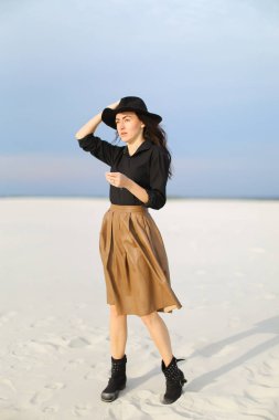 Kar üzerinde duran kız giyiyor etek, siyah bluz ve şapka, tek sesli arka plan.