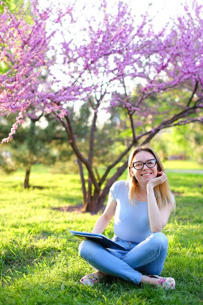 Gladden étudiante assise sur l'herbe verte avec dossier noir . — Photo