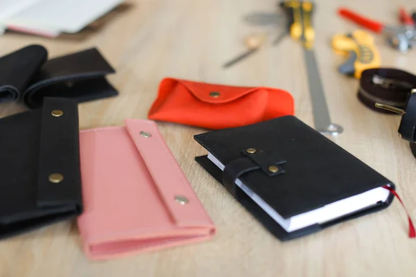 Stylish handmade leather wallets and notebook lying on table.
