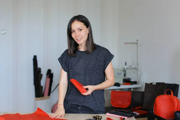 Jeune femme debout avec portefeuille en cuir rouge à l'atelier . — Photo