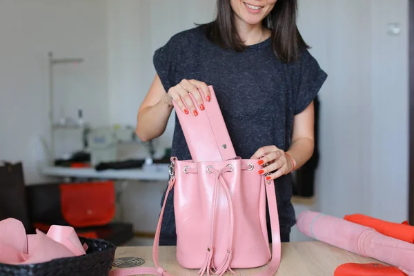 Pessoa feminina de pé com rosa saathe artesanal bolsa de mulher e carteira um atelier . — Fotografia de Stock