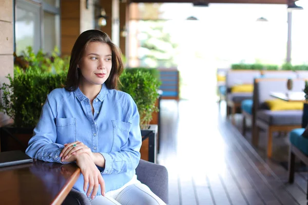 Mulher bonita sentada no café em plantas quarto fundo e vestindo camisa jeans — Fotografia de Stock