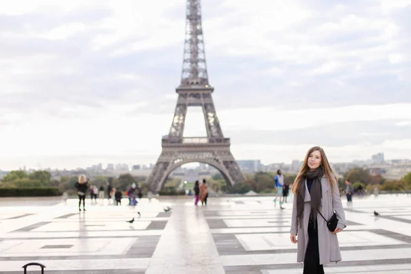 Vakker kvinne i grå frakk ved Eiffeltårnet i Paris. . – stockfoto