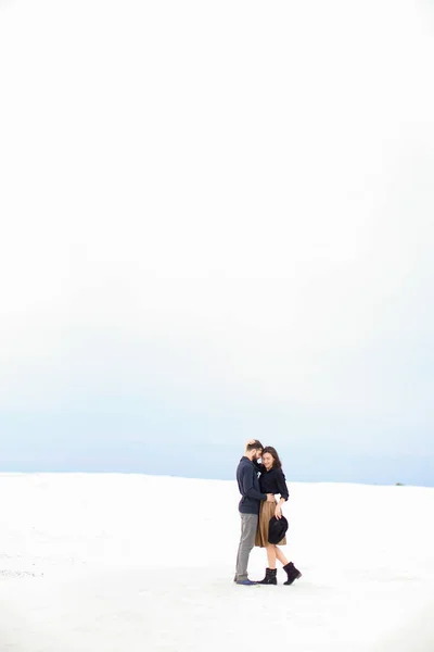 Cfucasian casal de pé em branco inverno monofônico fundo e abraço . — Fotografia de Stock