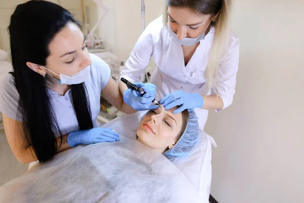 Maquillage professionnel de tatouage par un cosmétologue pour femme au cabinet avec infirmière . — Photo