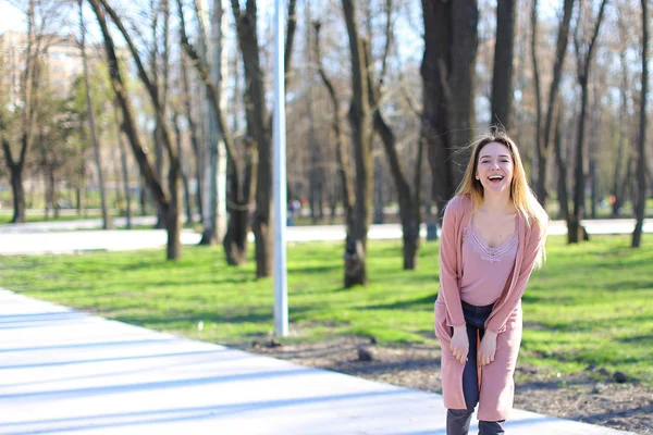 Sorridente ragazza carina guardando la fotocamera e passeggiando nel parco primaverile . — Foto Stock