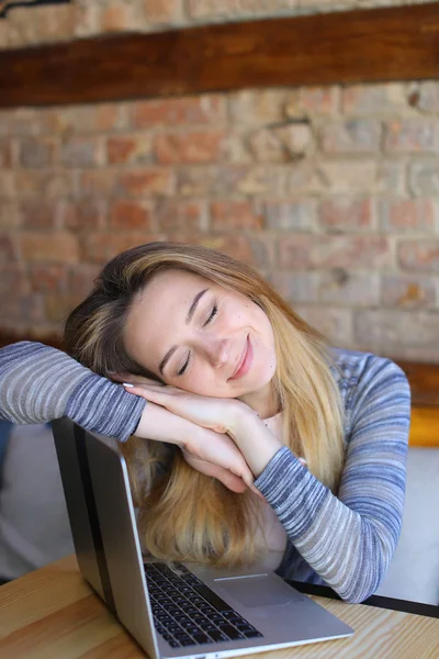 Chica bonita durmiendo cerca de la computadora portátil en la cafetería . — Foto de Stock