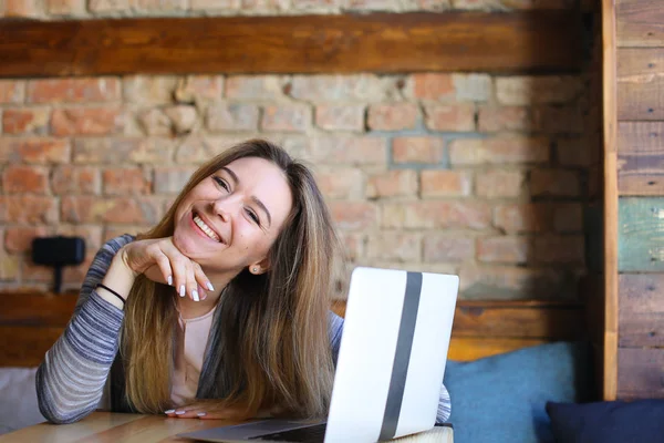 Mujer sonriente usando Internet por computadora portátil en la cafetería . — Foto de Stock