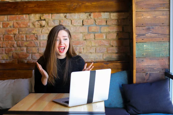 Sorprendido y decepcionado persona femenina utilizando el ordenador portátil y sentado en la cafetería . — Foto de Stock