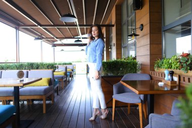 Kafe masalarda yakın duran ve smartphone, tutmak kız kot gömlek giymiş.