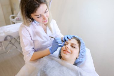 Genç güzellik uzmanı tarafından kaş dövme kalemi kadın için makyaj yapma.