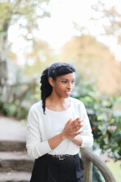 Blackyoung pretty girl wearing white blouse and pants in stone stairs background.