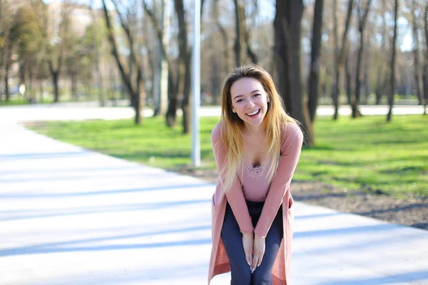 Bella ragazza guardando la fotocamera, sorridente e passeggiando nel parco primaverile . — Foto Stock