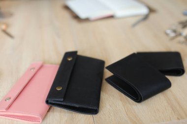 Siyah ve pembe sevimli el yapımı deri cüzdan ve masanın üzerinde yatan dizüstü.