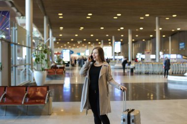 Güzel kız valiz ve smartphone ile konuşurken ile Havaalanı salonu gidiş.