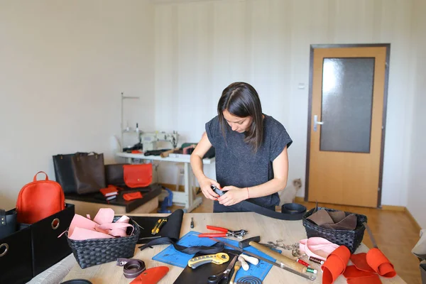 European craftswoman working at leather atelier near materials and tools.