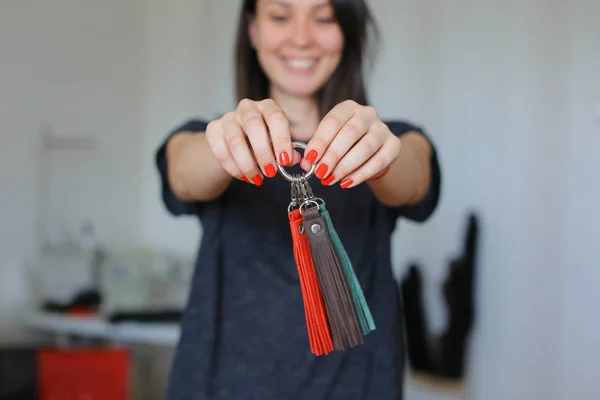 Femme souriante debout avec des bibelots faits à la main en cuir à l'atelier à la maison . — Photo