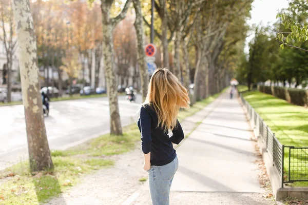 Jonge blonde vrouw lopen in de stad en genieten van de lente weer. — Stockfoto