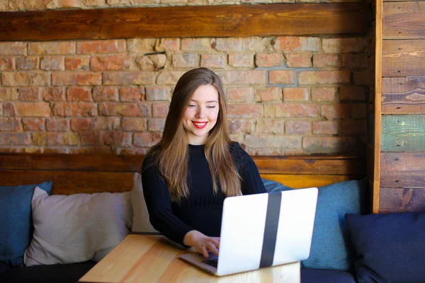 Γοητευτικό κορίτσι με κόκκινα χείλη που χρησιμοποιούν φορητό υπολογιστή στο café. — Φωτογραφία Αρχείου