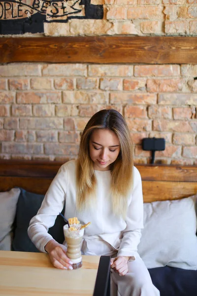 Junge Frau sitzt mit Tasse Kaffee am Tisch und posiert für Foto — Stockfoto